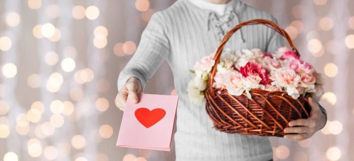 man holding basket full of flowers and postcard