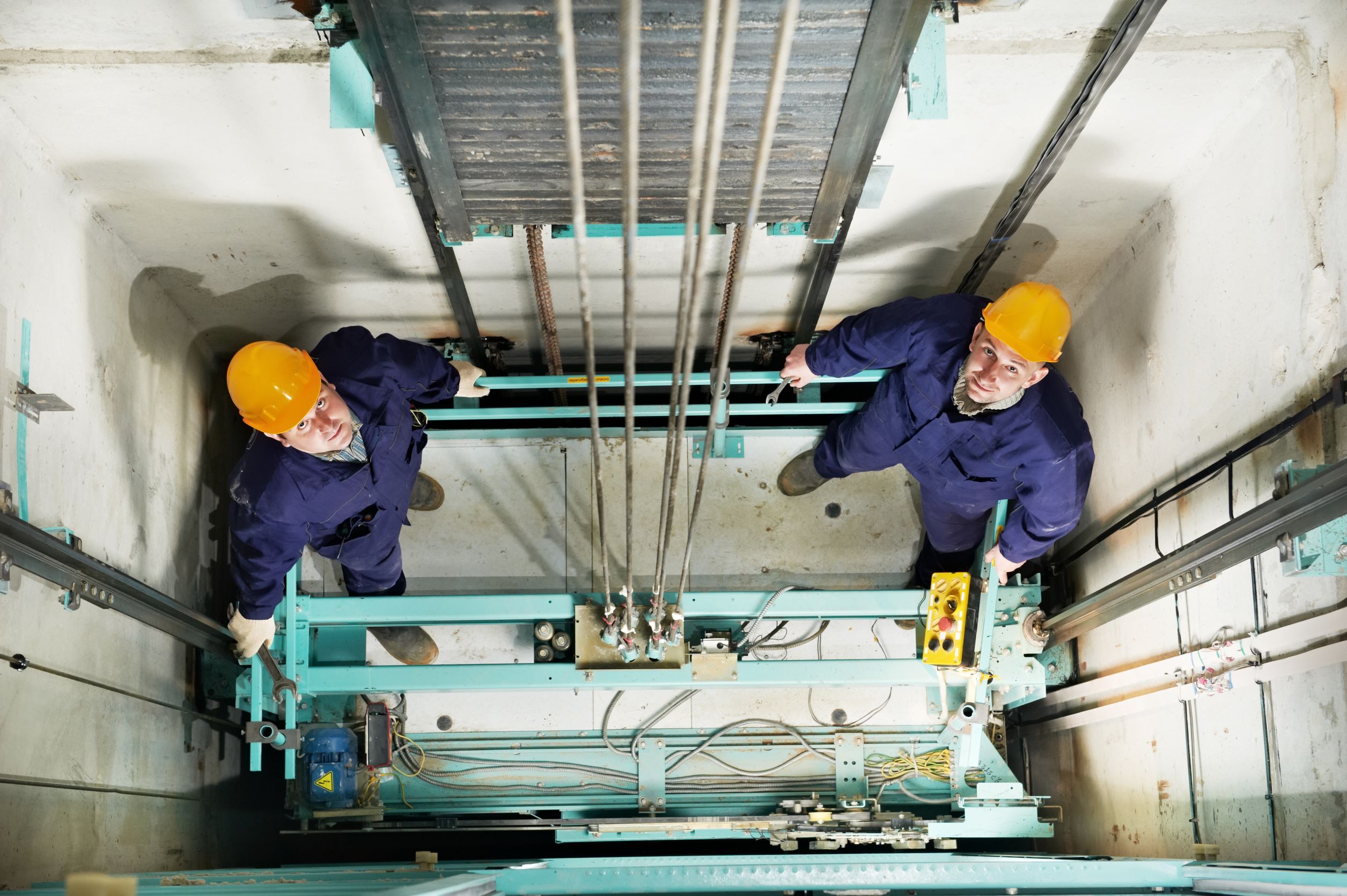 16404884_l-machinists adjusting lift in elevator hoist way
